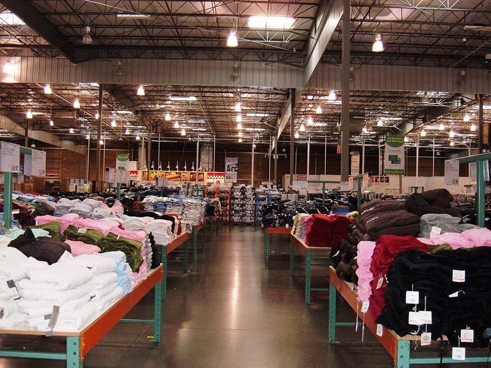 Costco ichida: beton pol, baland temir javonlar va poddonlarda turgan tovarlar. Bezakka sarflanmagan har bir dollar narxga tushadi.