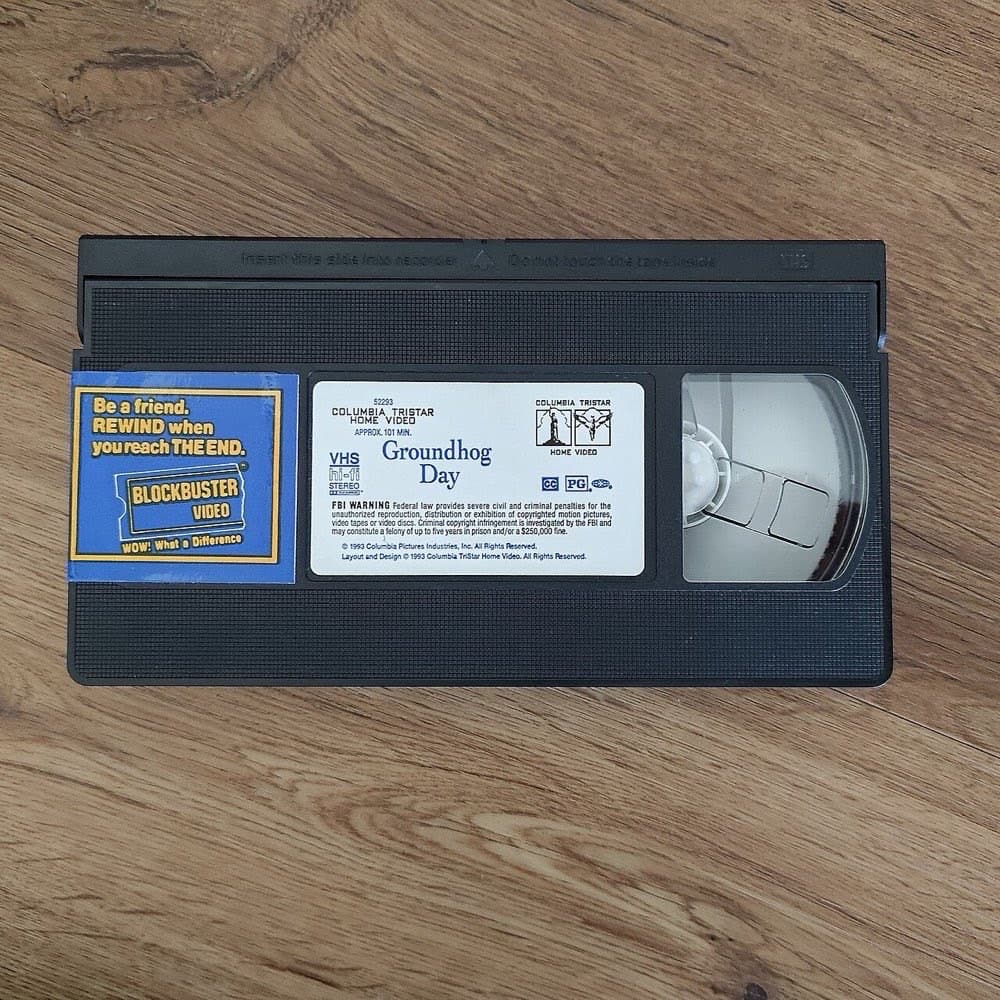 Blockbuster video kassetasi — "orqaga o'rang" eslatmasi bilan. Kassetani o'ramasdan yoki kech qaytarish qo'shimcha to'lovga olib kelishi mumkin edi.